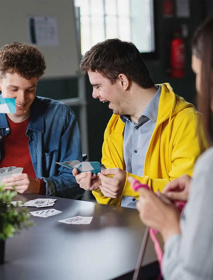 Friends laughing while playing cards together